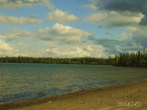 image of beach , lake and tree lined shores