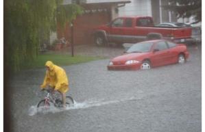 image of person riding bike through flooded Yorkton street
