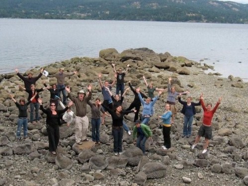 image of a group of people standing with arms extended on a rocky shore