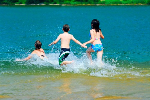image of 3 children splashing into the water at a lake