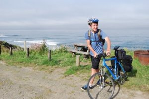 image of young man beside bike along water's edge